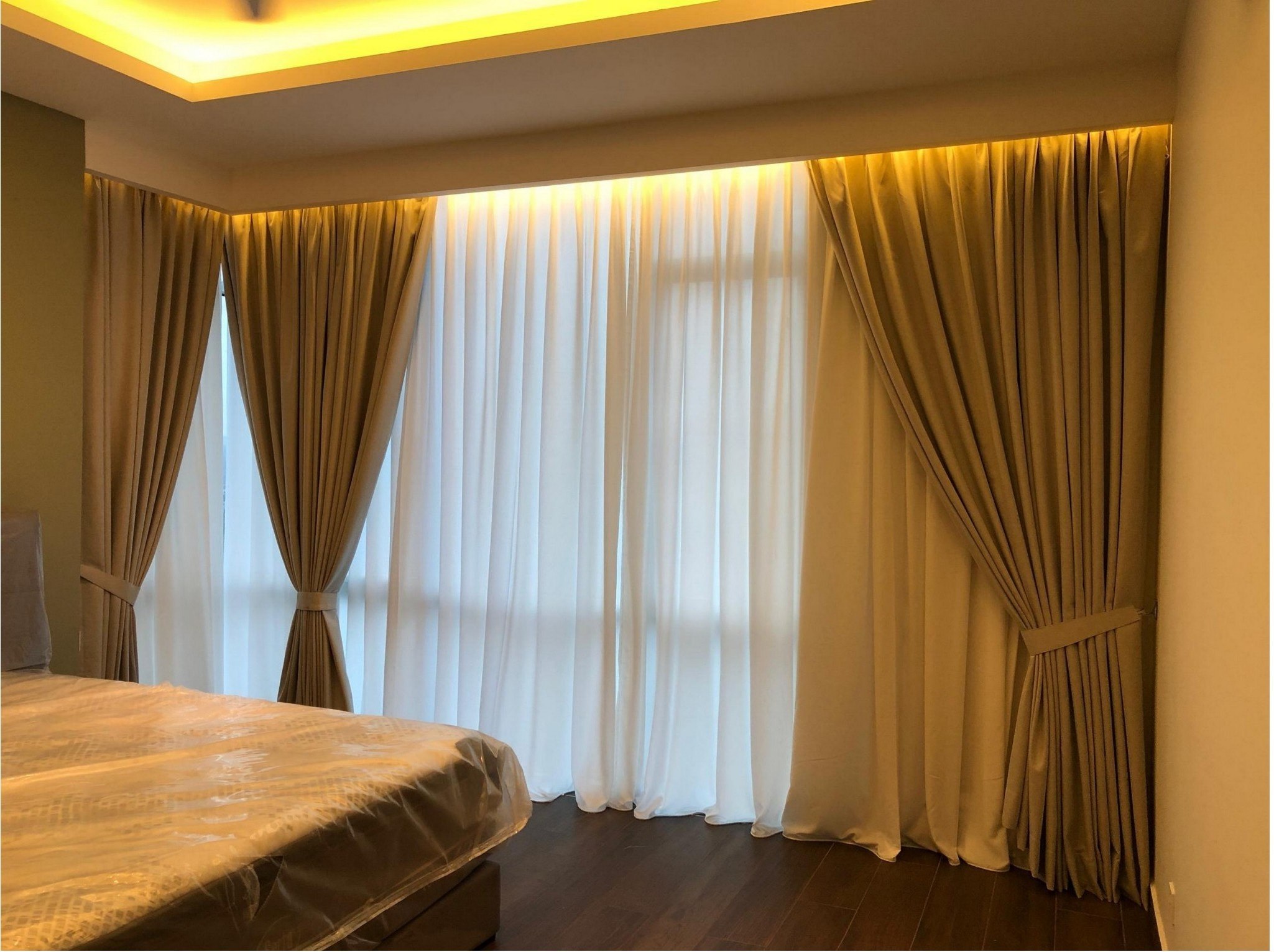 Tied-back beige curtains with white sheers in master bedroom