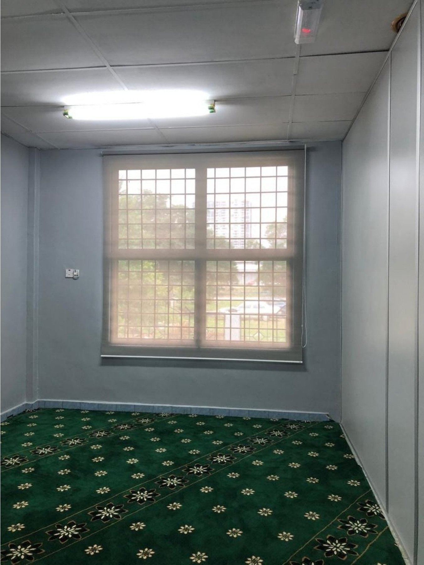 Roller blind in a Malaysian surau / prayer room with green carpet